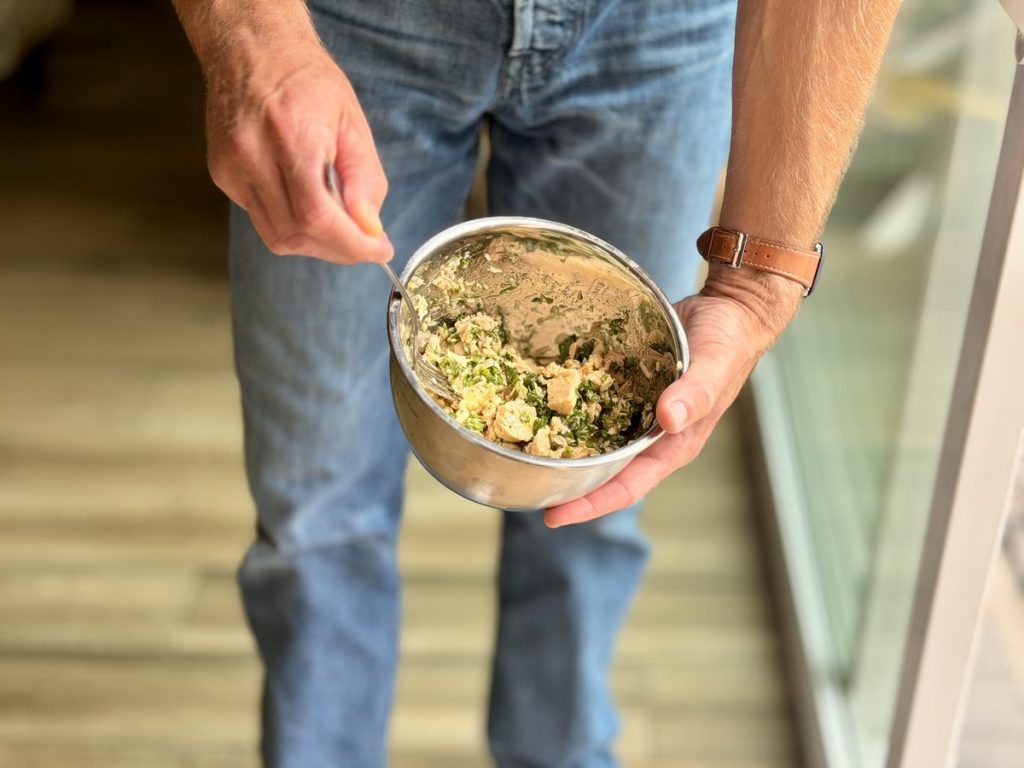A bowl of tuna pasta with lemon and parsley, held in two hands