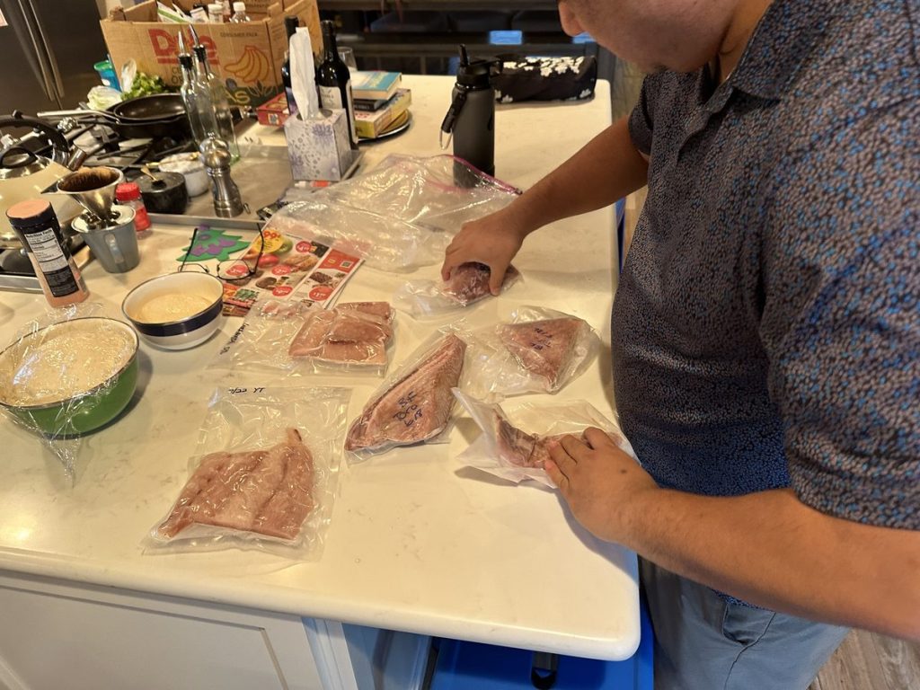 Raw fish fillets in vacuum-sealed bags laid out on a kitchen counter during a prep session